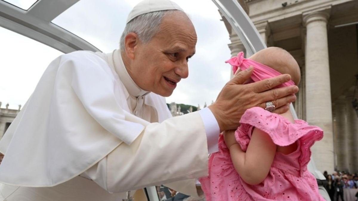El Papa saluda a una bebé al hacer el tradicional recorrido de los miércoles por la Plaza de San Pedro.