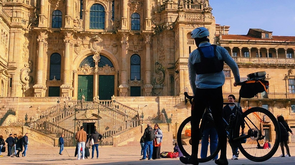 Un ciclista llega a la catedral de Santiago, quizá tras recorrer el Camino de Santiago