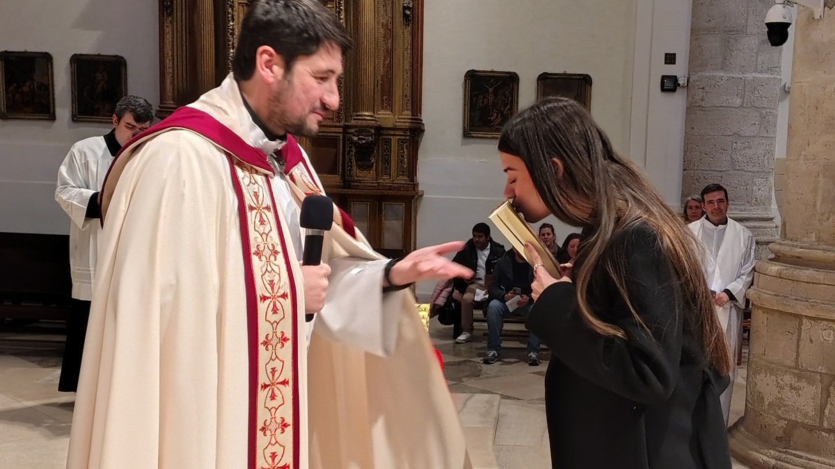 Una joven besa las Escrituras que ofrece el sacerdote Jesús Úbeda, uno de los Ritos de Ingreso al catecumenado