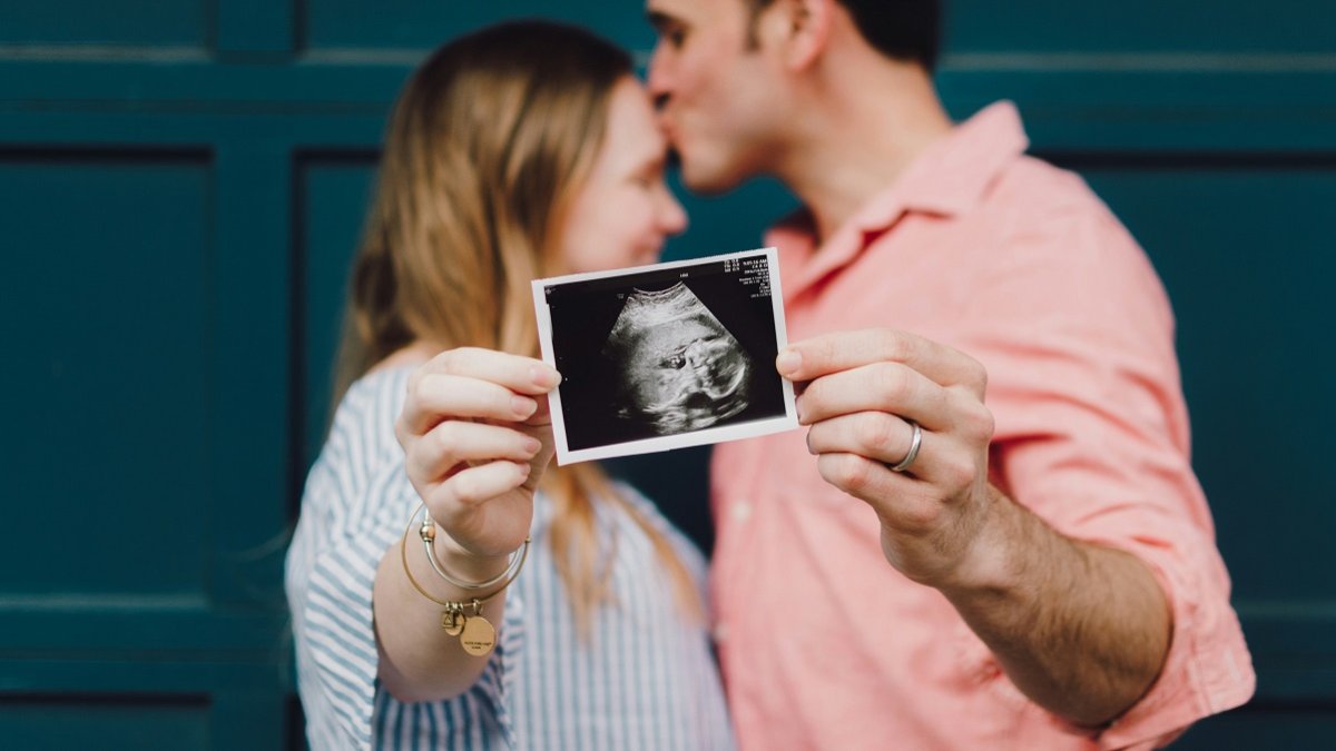 Una pareja muestra la ecografía de su bebé... en España hay un pequeño repunte de natalidad, que no compensa los fallecimientos