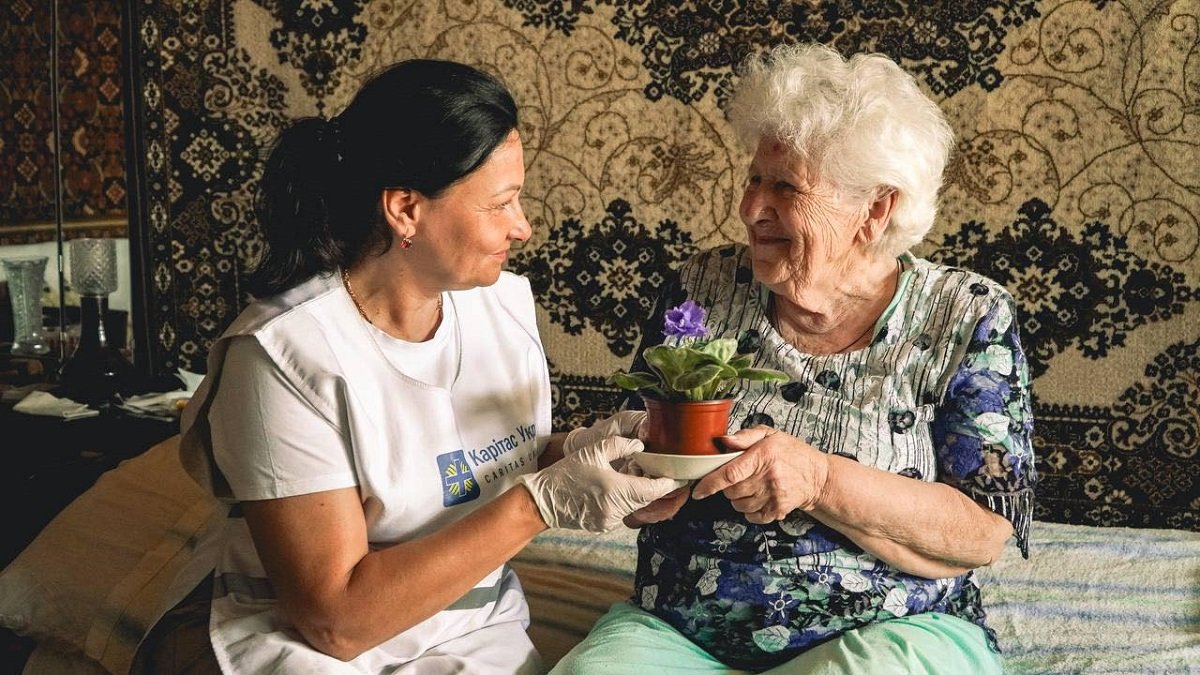 Una voluntaria de Caritas Ucrania visita a una anciana en la bombardeada Járkov en 2025