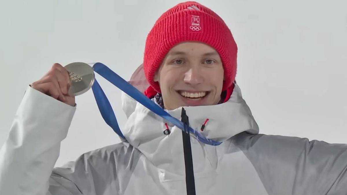 Kacper Tomasiak muestra la medalla de plata ganada en salto de trampolín normal individual.