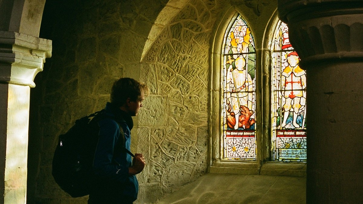 Un hombre en un laberinto oscuro busca la luz en las vidrieras, símbolo del deseo de libertad