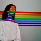 Una mujer con fondo de la bandera arcoíris.