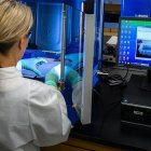 Una mujer científica con bata blanca, guantes y ordenador