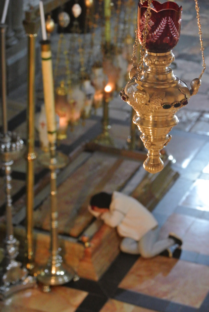 Una joven medita de madrugada sobre la Piedra de la Unción.