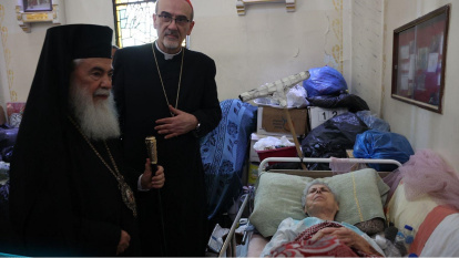 El Patriarca griego Teófilo y el cardenal Pizzaballa con una mujer herida en la parroquia latina de Gaza en julio de 2025