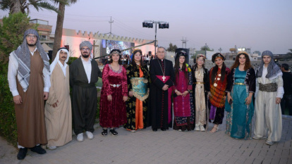 El obispo Bashar Warda, católico caldeo, y jóvenes con trajes de distintas etnias -árabe. kurda, yazidí- en el Festival de la Cruz en Erbil, 2025